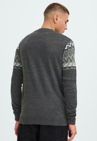 Grauer Strickpullover mit gemusterten Ärmeln in hellgrau, mit geometrischen Designs. Lange Ärmel und gerippter Saum sorgen für zusätzliche Textur.