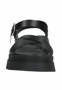 Black sandals with a thick sole, featuring crossed straps and an ankle buckle. Made of synthetic material, smooth texture, minimal design.