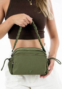 Borsa a tracolla verde oliva con manico intrecciato, realizzata in tessuto testurizzato, con due scomparti con zip e logo decorativo sul fronte.