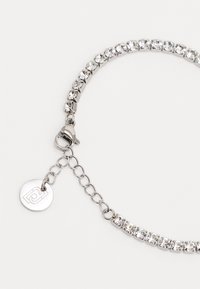 Bracciale d'argento con cristalli trasparenti incastonati in un design interconnesso. Presenta una chiusura a moschettone e una catena regolabile con un'etichetta rotonda con logo.