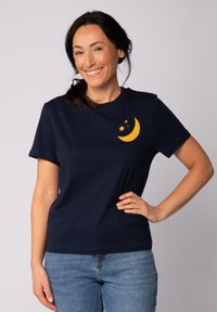 Navyblaue Baumwoll-T-Shirt mit einem Design aus einem gelben Halbmond und Sternen auf der linken Brust. Kurzärmlig und mit Rundhalsausschnitt.
