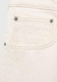 Bijeli denimski materijal s stražnjim džepom i akcentima od srebrnog metala, uz suptilne detalje šavova, koji daju teksturirani izgled.