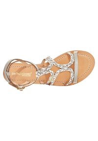 Sandalo con cinturini in beige chiaro e accenti metallici. Presenta cinturini intrecciati e una suola piatta. Progettato per comfort e utilizzo quotidiano.