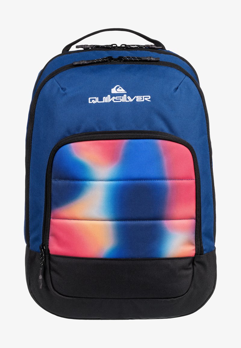 Mochila de tela azul con un bolsillo frontal de degradado colorido, patrones vibrantes en rosa, azul y naranja, y fondo negro. Logo exhibido en la parte superior.