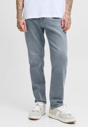 Lichtgrijze denim jeans met een rechte pijp, voorzien van zichtbare stiksels en een licht vervaagde textuur. Combinatie met neutrale sneakers.