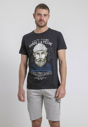 T-shirt en coton noir avec un graphique d'un homme barbu portant un bonnet tricoté et des rayures. Associé à un short cargo gris clair.