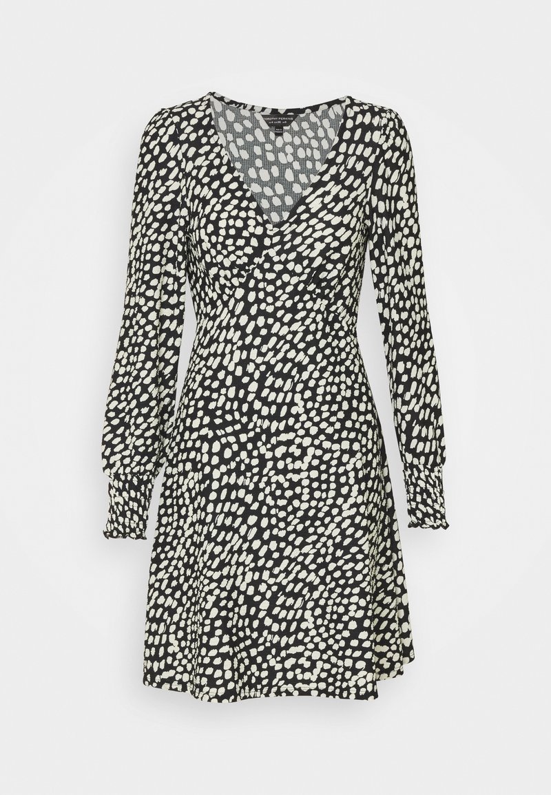 Svart klänning med vitt prickigt mönster, V-ringning, långa puffärmar och veckade muddar. Kjoldesign med utsvängd silhuett. Lätt tygstruktur.