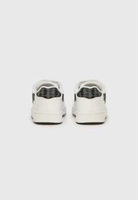 Λευκά αθλητικά παπούτσια με υφασμένο μαύρο μοτίβο στη φτέρνα. Λεπτό υλικό, στρογγυλεμένη μύτη και λαστιχένια σόλα. Μινιμαλιστικός σχεδιασμός.