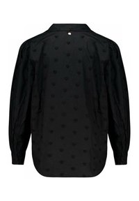 Blouse en coton noir avec col, manches longues et motifs de cœurs texturés sur le tissu. Fermeture à boutons au dos au niveau du cou.