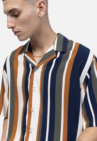 Kortärmad knäppskjorta med vertikala ränder i marinblått, orange, grönt och vitt. Tillverkad av ett lätt tyg.