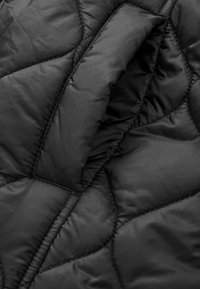 Jachetă puffer neagră, din material matlasat, cu o textură netedă, având cusături în formă de diamant și un detaliu cu guler pliat.