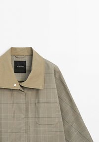 Beige and brown plaid jacket with large tan collar and snap button, showing upper front and right sleeve on white background.