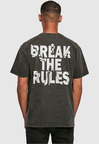 Zwart graphic t-shirt met opvallende witte tekst "BREAK THE RULES" op de achterkant. Korte mouwen en een ontspannen pasvorm met zichtbare stiksels.