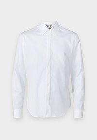 Λευκό πουκάμισο με μακριά μανίκια, φτιαγμένο από απαλό βαμβάκι, με μυτερό γιακά, πλαίσιο κουμπιών και στρογγυλή βάση με μανίκια που έχουν κουμπιά.