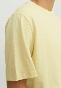 Lys gul kortærmet t-shirt lavet af blødt, struktureret stof. Har rund hals og rene syninger langs kanten.