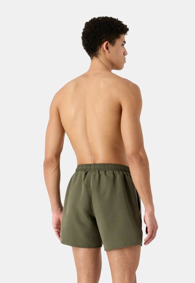 Bañador de hombre verde oliva con cinturilla elástica, tejido suave y aberturas laterales para mayor movilidad. Presenta un diseño de corte relajado.