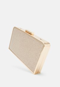 Obdélníkové psaníčko ve zlatém tónu s přední částí s tkaným vzorem, hladkým pevným pouzdrem a horním zapínáním na sponu. Vyznačuje se elegantním designem s ostrými úhly.