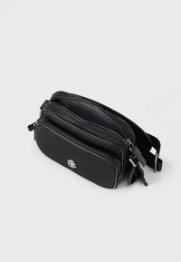 Borsa nera con parte frontale testurizzata, due scomparti con cerniera e dettagli in argento. Forma compatta, materiale liscio, tracolla regolabile.