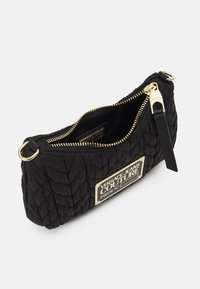 Pochette nera trapuntata di Versace Jeans Couture con zip dorata, targhetta logo dorata e linguetta in pelle per la zip, mostrata parzialmente aperta.
