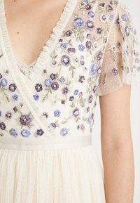 Elfenbeinfarbenes Kleid mit floraler Stickerei in Lila und Blau, mit V-Ausschnitt, transparenten Puffärmeln und einem Satinbund, strukturierter Stoff.