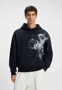 Felpa con cappuccio blu navy in misto cotone, caratterizzata da una grande stampa astratta bianca sul davanti, con vestibilità rilassata e polsini e fondo a coste.