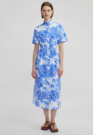 Vestido de camisa floral azul con mangas cortas, cintura ajustada y cierre de botones. Hecho de algodón, presenta un fondo blanco y un diseño fluido.