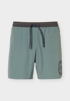 Lettere grønne badeshorts for menn med mørkegrå elastisk linning, svart snøring og en sirkulær sol-logo på venstre ben.