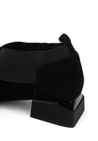 Musta mokkanahkainen nilkkurit matalalla lohkokorolla ja joustavalla sivupaneelilla helppoa pukemista varten.