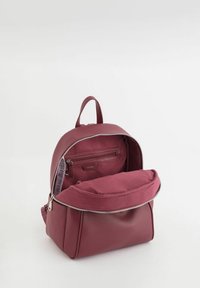 Sac à dos en cuir mauve de forme arrondie, avec une ouverture supérieure zippée et une poche frontale. Texture lisse avec un léger détail de grain.