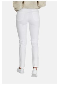 Witte denim jeans met een slim fit, voorzien van twee achterzakken en een eenvoudige uitstraling. Gecombineerd met witte sneakers. Gebreide trui zichtbaar.