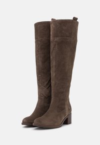 Bottes hautes jusqu'au genou en daim marron avec un bout arrondi et un petit talon bloc. Elles comportent un panneau élastique pour un bon ajustement et des languettes au sommet pour les enfiler.