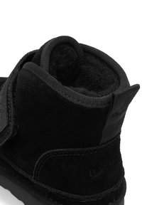 Czarny zamszowy botek za kostkę z fakturowaną cholewką, zapinany na pasek, z miękką podszewką i wzmocnionym obcasem dla lepszego wsparcia.