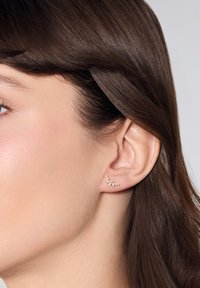 Złote kolczyki wkrętki z designem w formie klastra, ozdobione małymi, przezroczystymi kryształkami o różnych rozmiarach, które prezentują delikatną i nowoczesną estetykę.