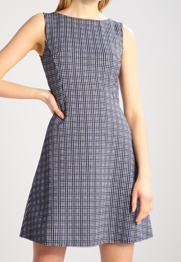Robe sans manches à carreaux bleu marine et blanc avec un col rond, un buste ajusté et une jupe évasée. Tissu lisse avec des détails de texture subtils.