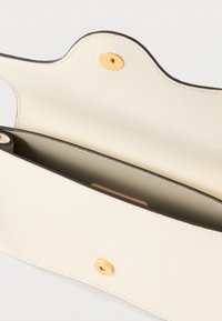 Mala de pele cremosa com textura suave, borda superior recortada em ondas e fecho de pressão dourado. O interior possui um compartimento simples.