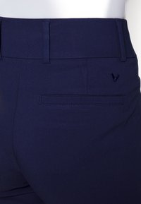 Námornícke modré nohavice majú plochý predný dizajn, standardný pás a zadnú vrecko s decentným vyšitým logom.