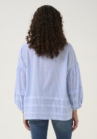 Ljust blå och vit randig blus med vida ärmar, avslappnad passform och subtila veck vid fållen. Tillverkad i bomull, med en avslappnad design.