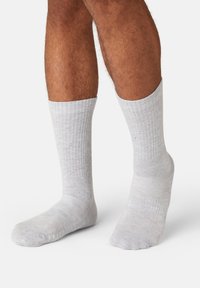 Light gray ribbed socks made from a soft fabric, featuring a mid-calf length and a reinforced toe and heel design.
