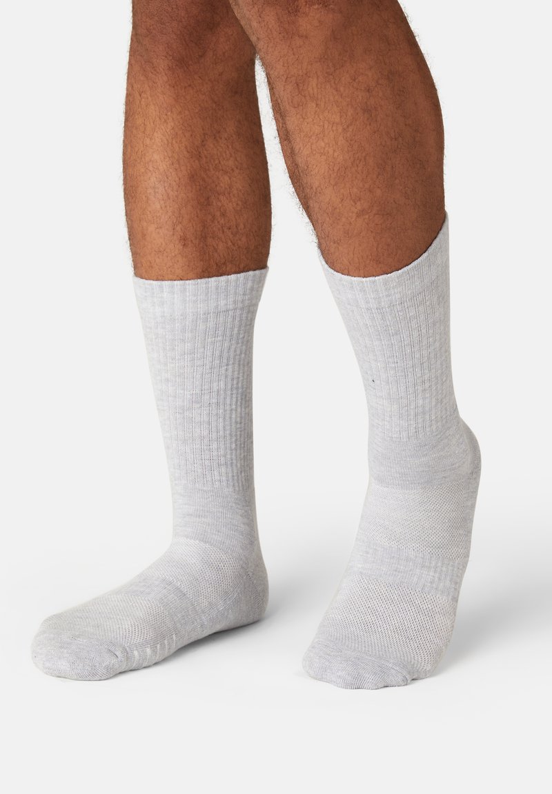 Light gray ribbed socks made from a soft fabric, featuring a mid-calf length and a reinforced toe and heel design.