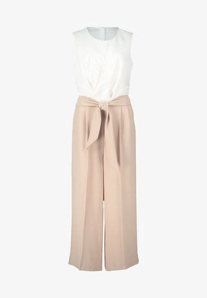 Fehér, ujjatlan felső, csavaros elülső résszel, magas derekú, laza fazonú bézs nadrággal, amelyhez kötőszalag jár.