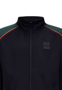 Zwarte sportjacket met een hoge kraag, voorzien van groene schouderpanelen, rode accenten, een rits aan de voorkant en een vierkant logo op de borst.