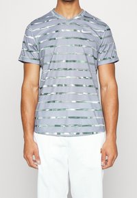 Camisa gris de manga corta con cuello en V, que presenta un patrón de rayas horizontales en verde y plata. Fabricada con un material suave y ligero.