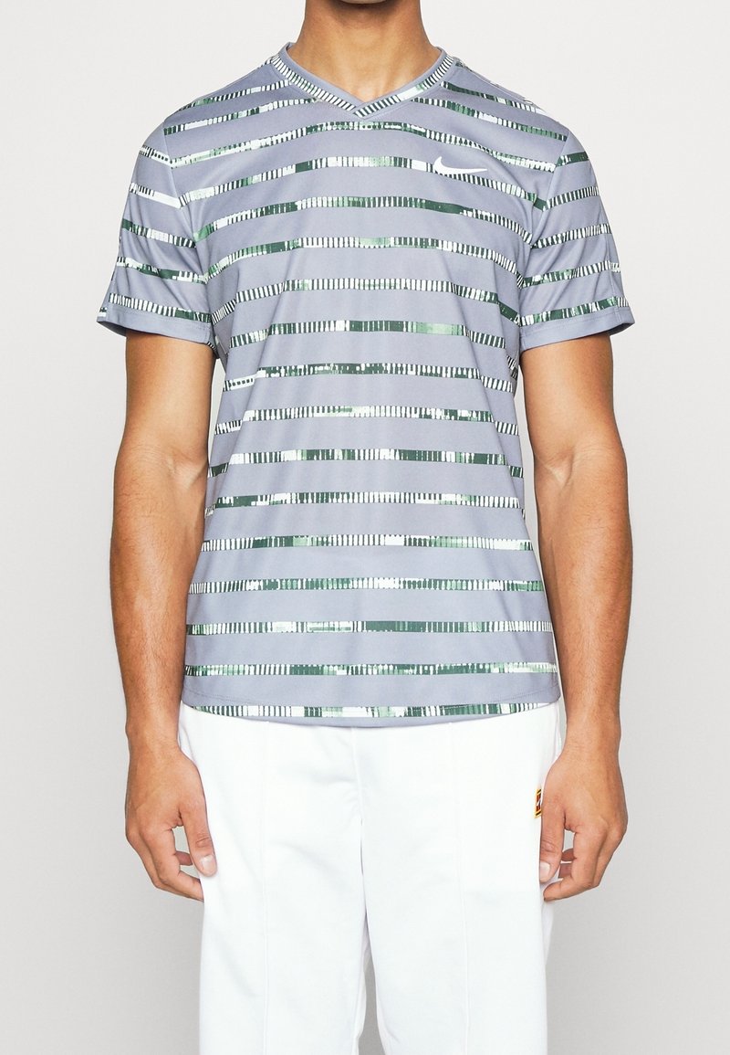 Camisa gris de manga corta con cuello en V, que presenta un patrón de rayas horizontales en verde y plata. Fabricada con un material suave y ligero.