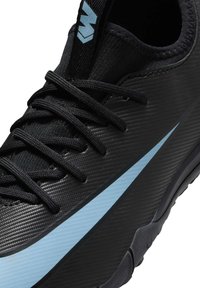 Zapatilla deportiva negra con un upper texturizado, cordones negros y una franja de acento azul a lo largo del costado. Incluye un cuello ligeramente acolchado.