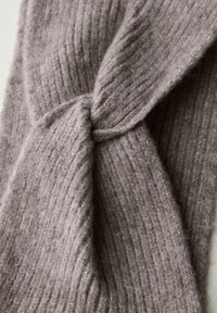 Tissu en tricot taupe côtelé doux noué en un nœud lâche, mettant en valeur la texture et le matériau confortable.