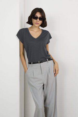 T-shirt v-neck gris foncé avec des manches courtes, associé à un pantalon large gris clair et une ceinture noire, présenté sur fond blanc.