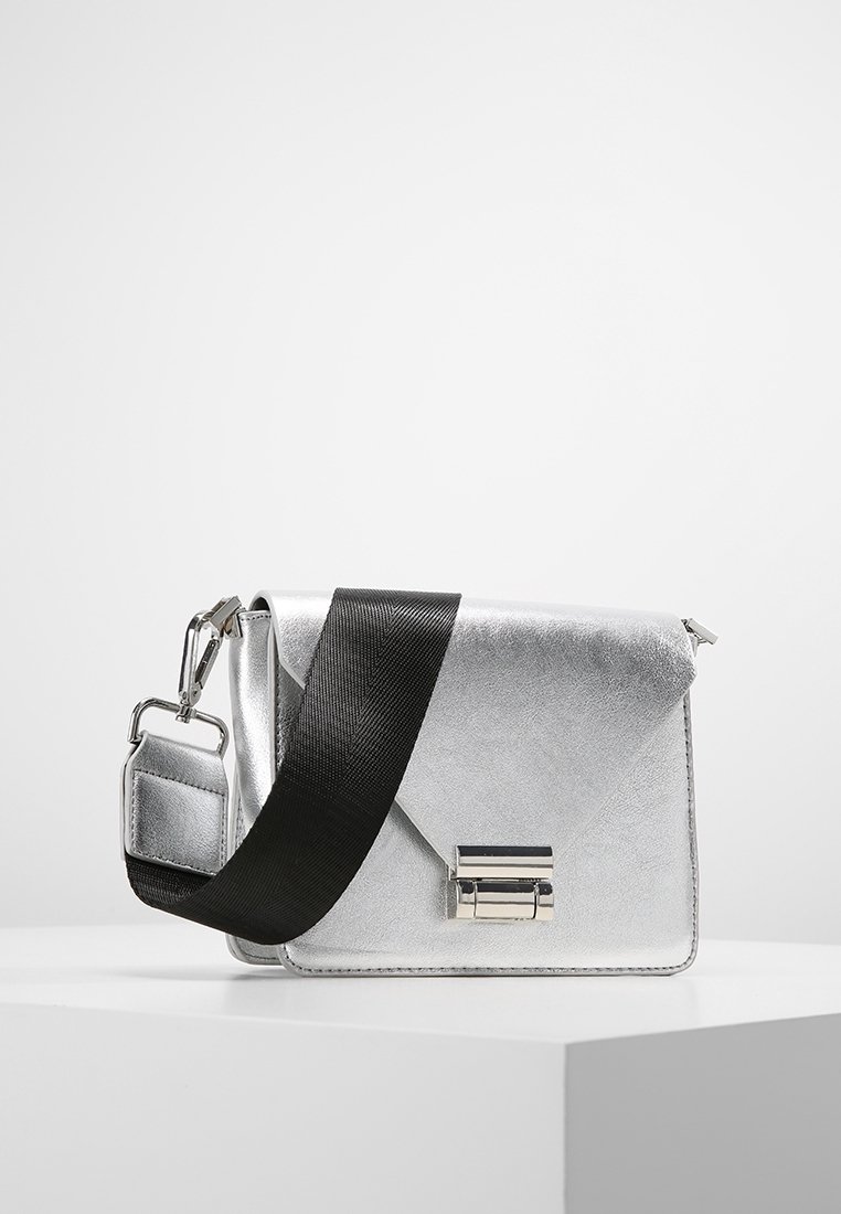 Stříbrná syntetická kabelka s elegantním trojúhelníkovým klopovým designem, vybavená černým textilním páskem a stříbrným kovovým zapínáním.