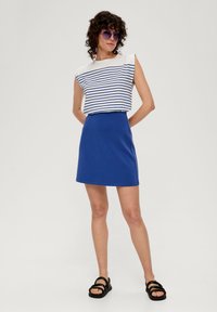 Gestreiftes ärmelloses Oberteil in Weiß und Blau, kombiniert mit einem einfarbigen blauen Rock. Schwarze Riemchensandalen vervollständigen das Outfit. Flache Textur, lässiges Design.