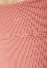 Ροζ ριγέ ύφασμα με οριζόντιες γραμμές, που διαθέτει μια διακριτική λευκή λογότυπη Nike και ενισχυμένες ραφές κατά μήκος των ενώσεων.