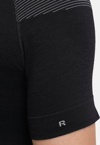 Chemise de sport noire à manches courtes, avec de fines rayures horizontales sur l'épaule et un "R" blanc brodé sur le revers.